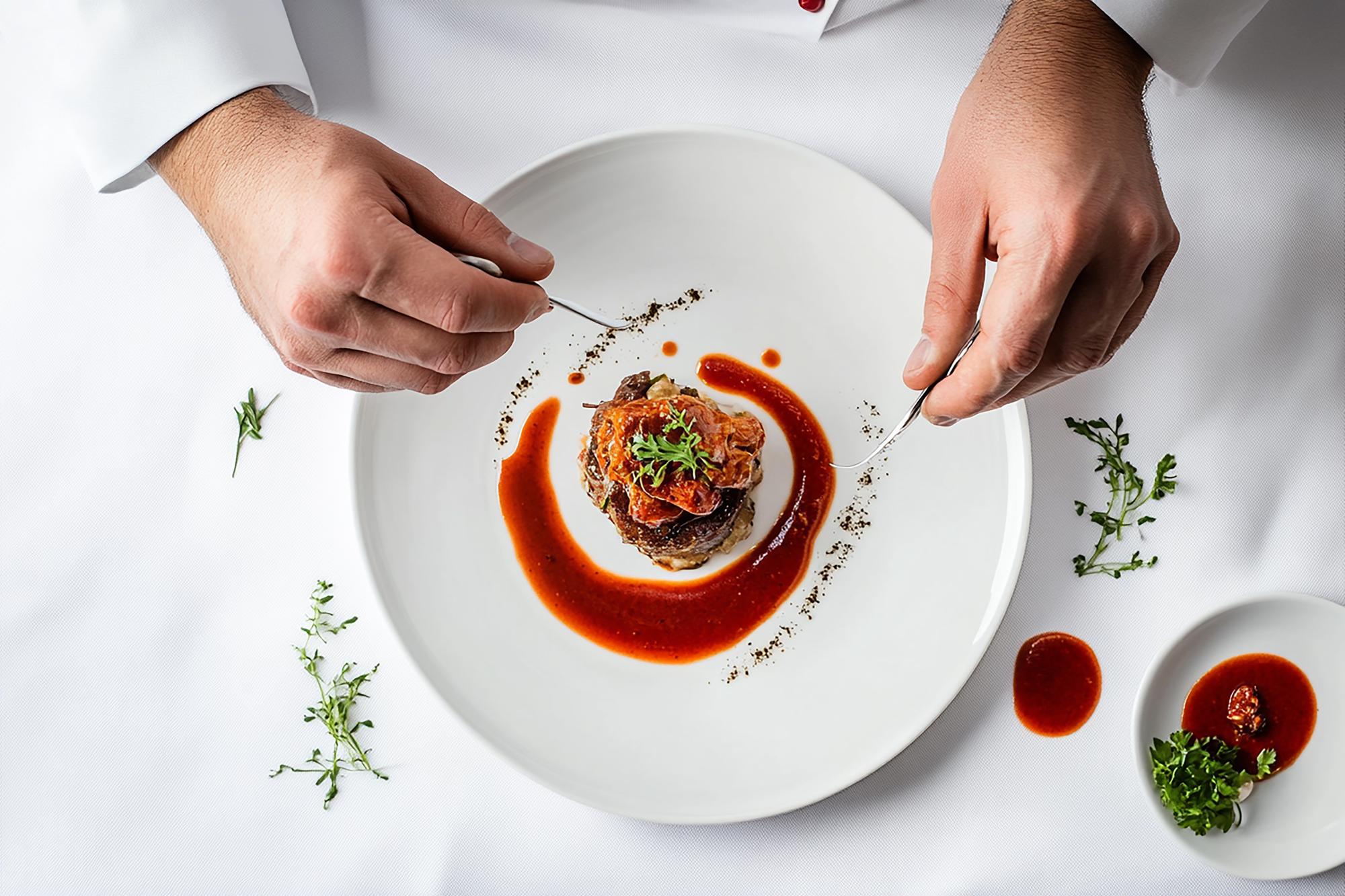 Chef preparing plated dish with gold accents